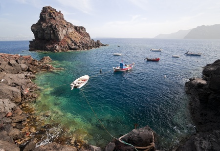 Fish-boats in the beautiful water near the pebble beachの写真素材