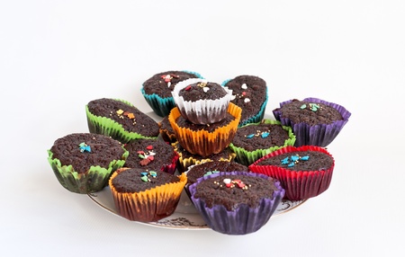 Chocolate muffins with sprinkles in paper cases on the plateの写真素材