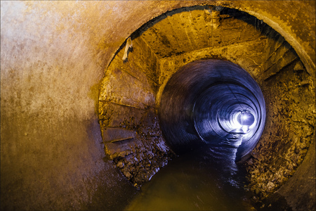 Dirty urban sewage flowing throw round sewer tunnel pipe