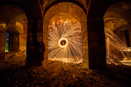 Freezelight using spinning burning steel wool and pyrotechnics in the ruins of castle. Trajectories of burning sparksの写真素材