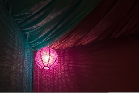 Pink Chinese paper lantern on a pink and blue textile background.の写真素材