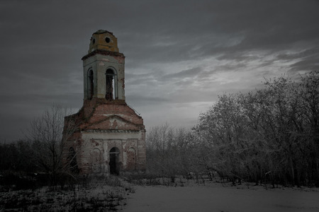 Ruined bell tower. Ruins of church on gray depressive winter background.の写真素材