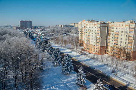 Winter Voronezh cityscape. Frozen trees in a forest covered by snow and hoarfrost near modern houses in the city of  Voronezh.の写真素材
