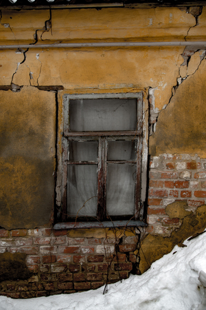 Shabby grungy cracked wall, broken windows, abandoned house, winter, poverty concept.の写真素材