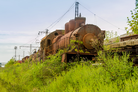 Abandoned train. Abandoned railway. Old rusty steam locomotive overgrown by plants.の写真素材