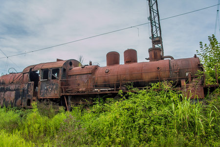Abandoned train. Abandoned railway. Old rusty steam locomotive overgrown by plants.