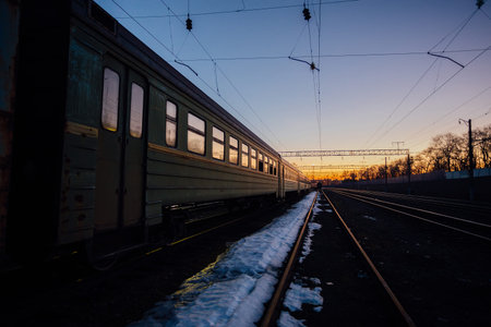 Railway with old passenger train in sunset background.