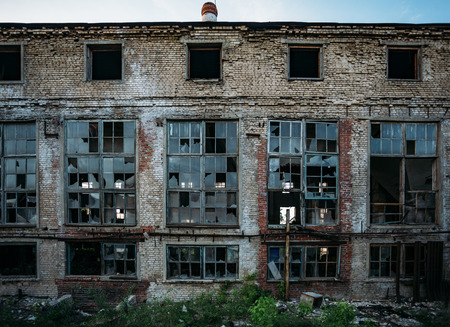 Abandoned industrial building facade, broken windows, shabby walls.の写真素材
