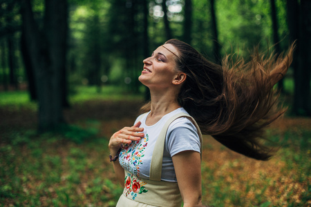 Smiling beautiful girl with waving hair in Russian dress with embroidery in forest.の写真素材
