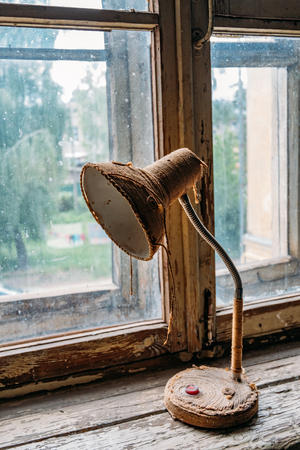 Old vintage reading lamp coiled with a string on old window sill.の写真素材