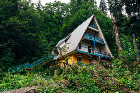 Old overgrown by trees ruined abandoned house in mountain forest.の写真素材