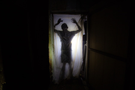 Human silhouette behind packing film in dark creepy room of abandoned building.の写真素材
