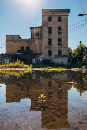 Abandoned building reflected in pool of rainwater.の写真素材