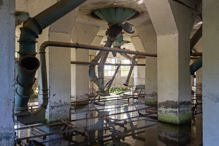 Flooded abandoned ruined flour mill factory. Old rusty pipes in dirty water.の写真素材