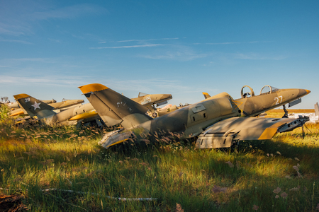 Abandoned broken old Soviet military fighter airplanes on grassy ground.の写真素材