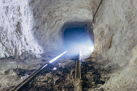 Dark creepy dirty abandoned mine tunnel with remnants of narrow-gauge railway