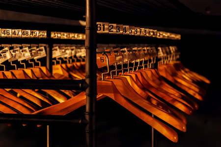 Wooden hangers with numbers in dark cloakroom.の写真素材