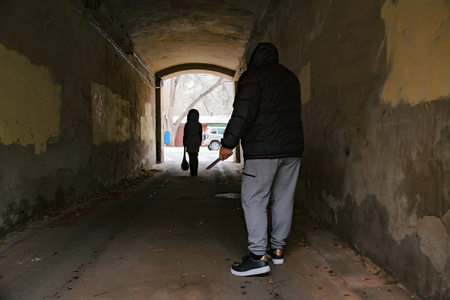 Unknown criminal guy with knife chasing young girl in arch tunnel. Robbery or rape in gangster district conceptの写真素材