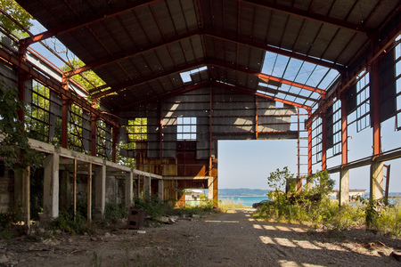 Ruined abandoned industrial building. Overgrown remains of rusty frame.の写真素材