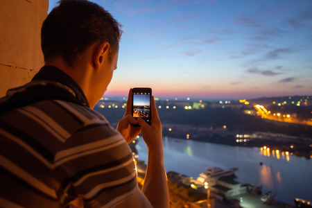 Young male taking picture of Sevastopol Bay from rooftop by smartphone cameraの写真素材