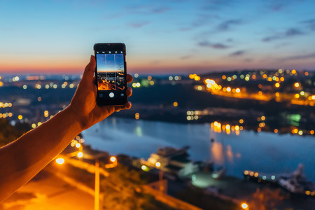 Male tourist's hand with smartphone taking picture of Sevastopol bay from rooftop. Tourism concept.の写真素材