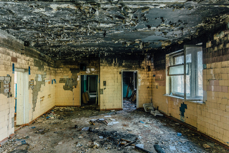 Burned interiors after fire of industrial or residential building. Charred tilled wall. Fire consequences concept.