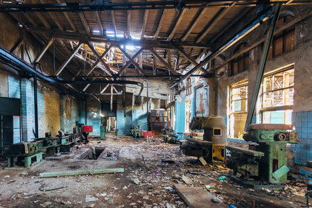 Old abandoned factory with rusty remains of industrial machine tools in workshop
