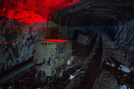 Dirty abandoned uranium mine with rusty rail and trolley