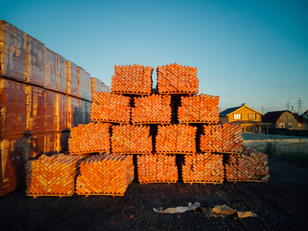 Stack of orange bricks packs on new construction site.の写真素材
