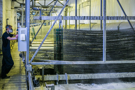 Worker pickling aluminium parts in tanks with etching acid to remove oxide cover.