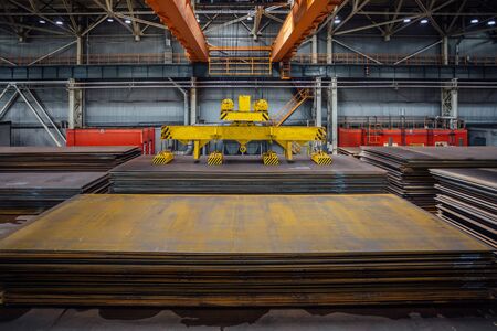 Overhead crane with magnetic grippers lifting steel sheets.の写真素材