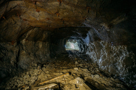 Dark dirty abandoned uranium mine with rusty remnants of railway.