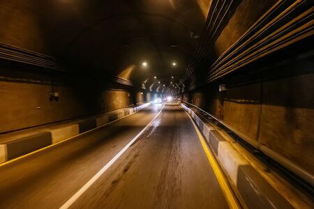 Road tunnel in mountain illuminated by lamps.の写真素材