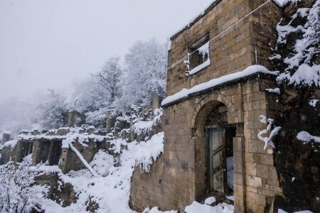 Old antique abandoned city Gamsutl in foggy snowy winter Caucasus mountains, Dagestan, Russia.の写真素材