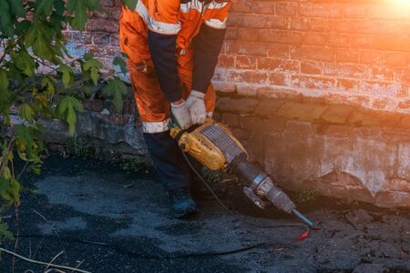 Road worker drilling asphalt on pavement with jackhammer.の写真素材