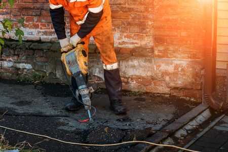 Road worker drilling asphalt on pavement with jackhammer.の写真素材