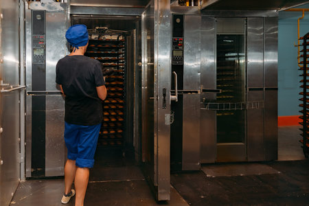 Confectionery manufacturing. Baker puts cookies into oven for baking.
