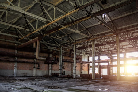 Old abandoned industrial building with rusty remnants of pipeline.