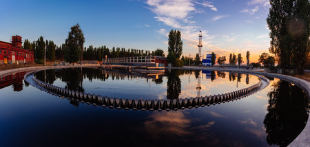 Modern sewage treatment plant. Round wastewater purification tanks at sunset, aerial view.