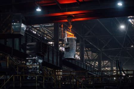 Iron casting at the foundry. Overhead crane with ladle with molten metal at metallurgical factory.の写真素材