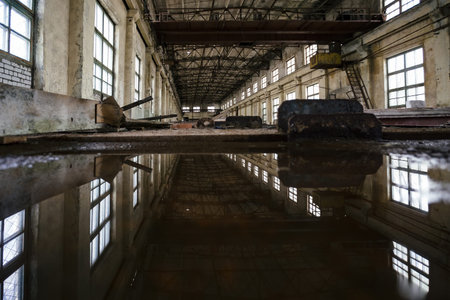 Inside of flooded dirty abandoned ruined industrial building with water reflection.