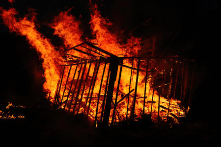 Burning wooden building at night, close up view.