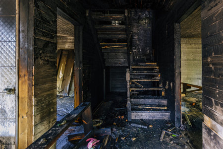 Burnt wooden house interior. Charred stairs and walls. Consequences of fire.
