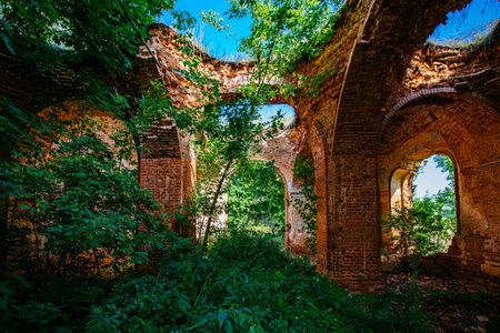 Old ancient abandoned red brick ruins overgrown by plants.の写真素材