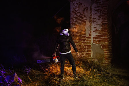 Maniac in mask of plague doctor with chainsaw.