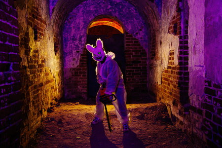 Maniac in mask of scary rabbit with chainsaw.