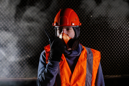 Man in respirator talking on walkie-talkie during fire in industrial building