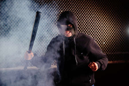 Masked angry man with bat in smoke.の写真素材