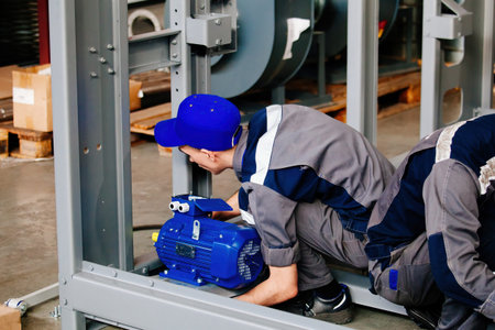 Factory workers assembling metal equipment in workshop.