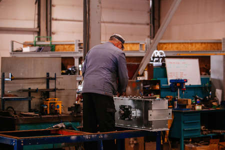 Factory workers assembling industrial equipment in workshop.の写真素材